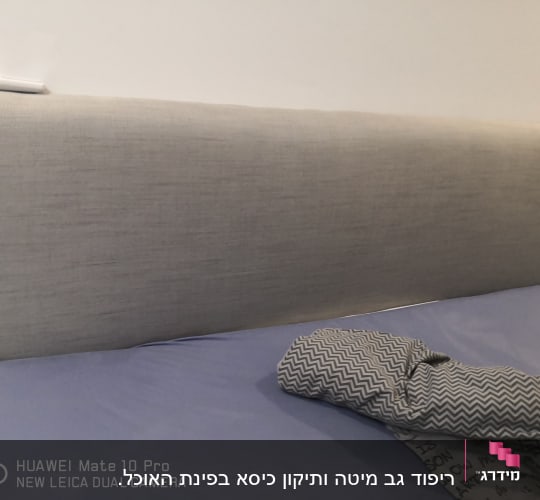 ראש מיטה מרופד בבד אפור עם כרית על המיטה
